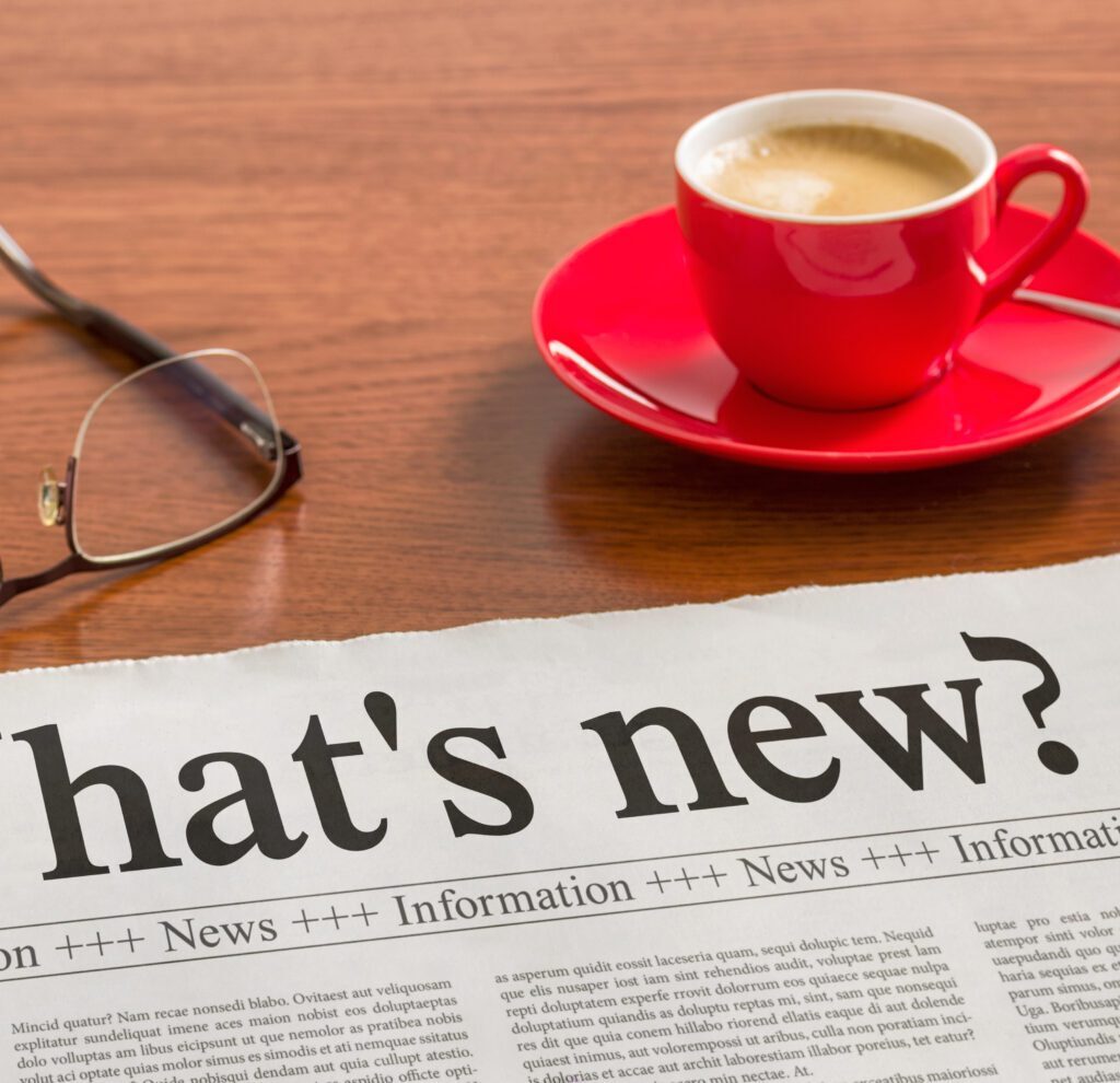 a newspaper with a cup of coffee and glasses on a table