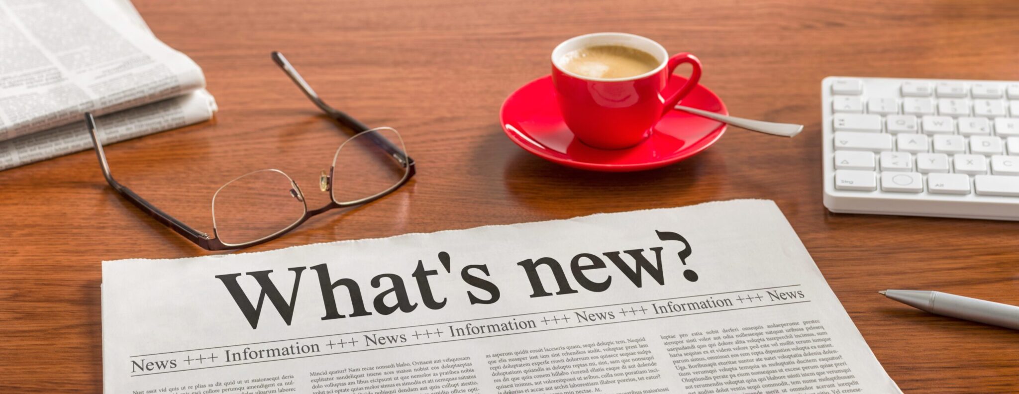 a newspaper with a cup of coffee and glasses on a table