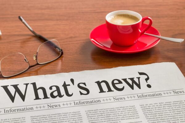 a newspaper with a cup of coffee and glasses on a table