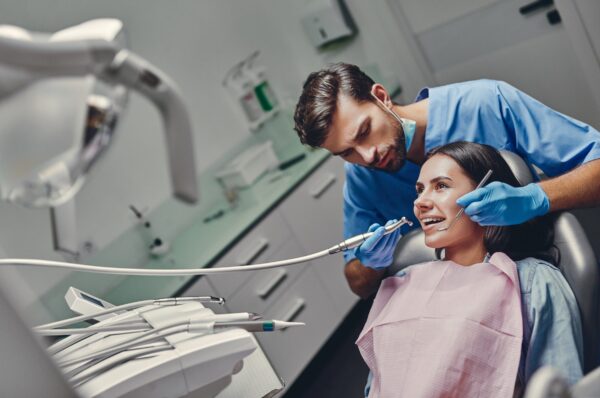 Attractive young woman in stomatology clinic with male dentist. Healthy teeth concept.