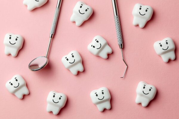 Healthy white teeth are smiling on pink background and dentist tools mirror, hook