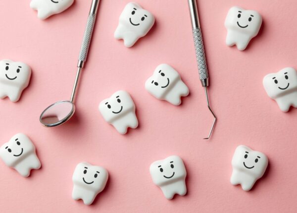 Healthy white teeth are smiling on pink background and dentist tools mirror, hook