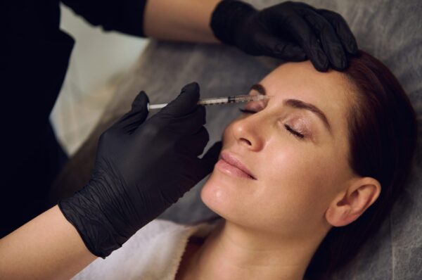 Beautiful middle aged European woman getting beauty injections on her face in wellness spa cosmetology clinic. Botulinum toxin injection and hyaluronic acid for anti-wrinkle anti-aging therapy