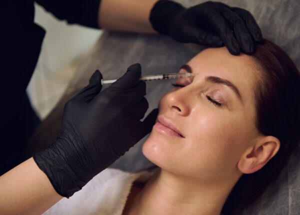 Beautiful middle aged European woman getting beauty injections on her face in wellness spa cosmetology clinic. Botulinum toxin injection and hyaluronic acid for anti-wrinkle anti-aging therapy